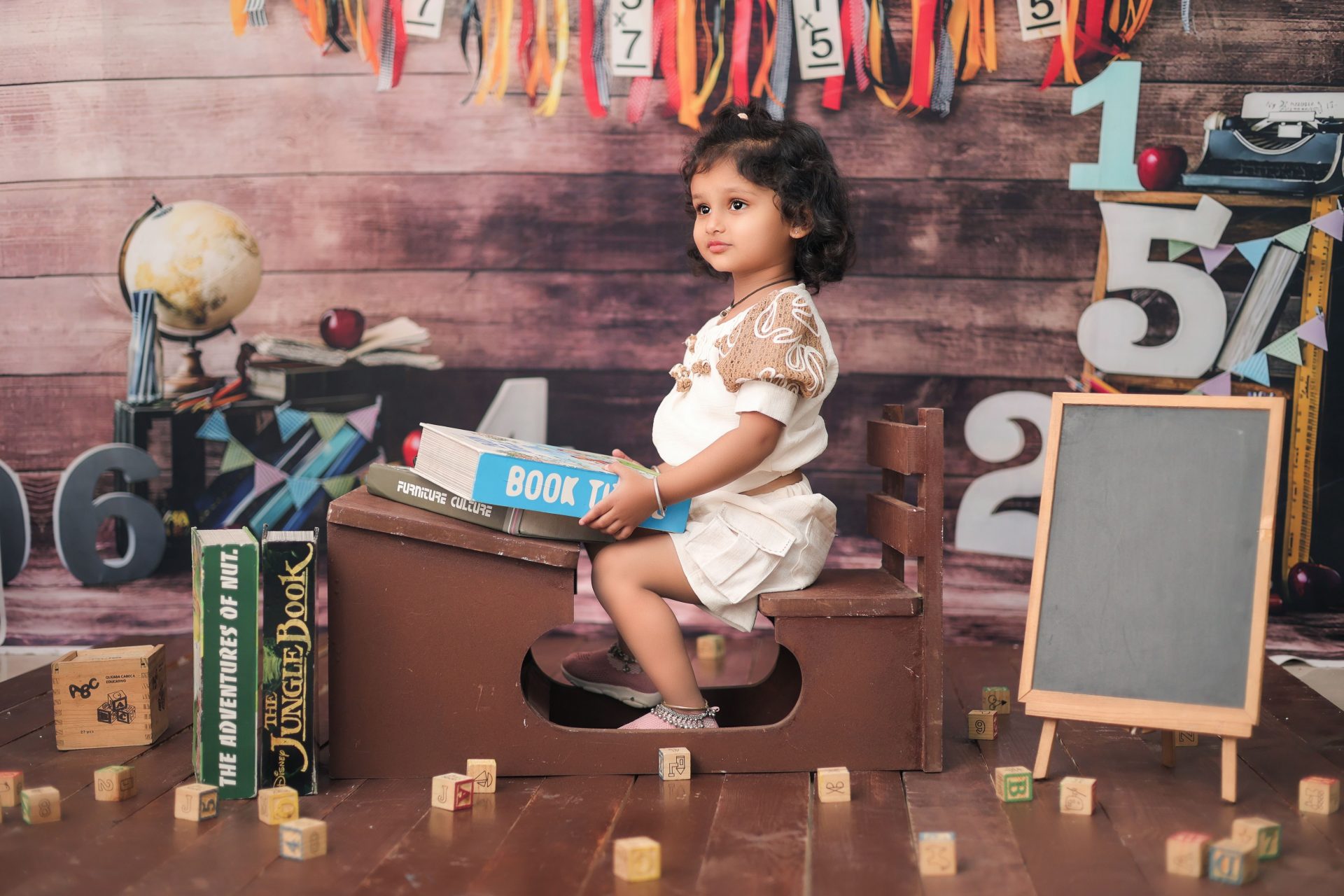 Adorable child in a classroom setting with books and educational props, creating a playful learning atmosphere.